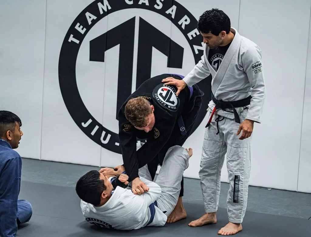 Team Casarez instructor coaching two adult students through a guard pass