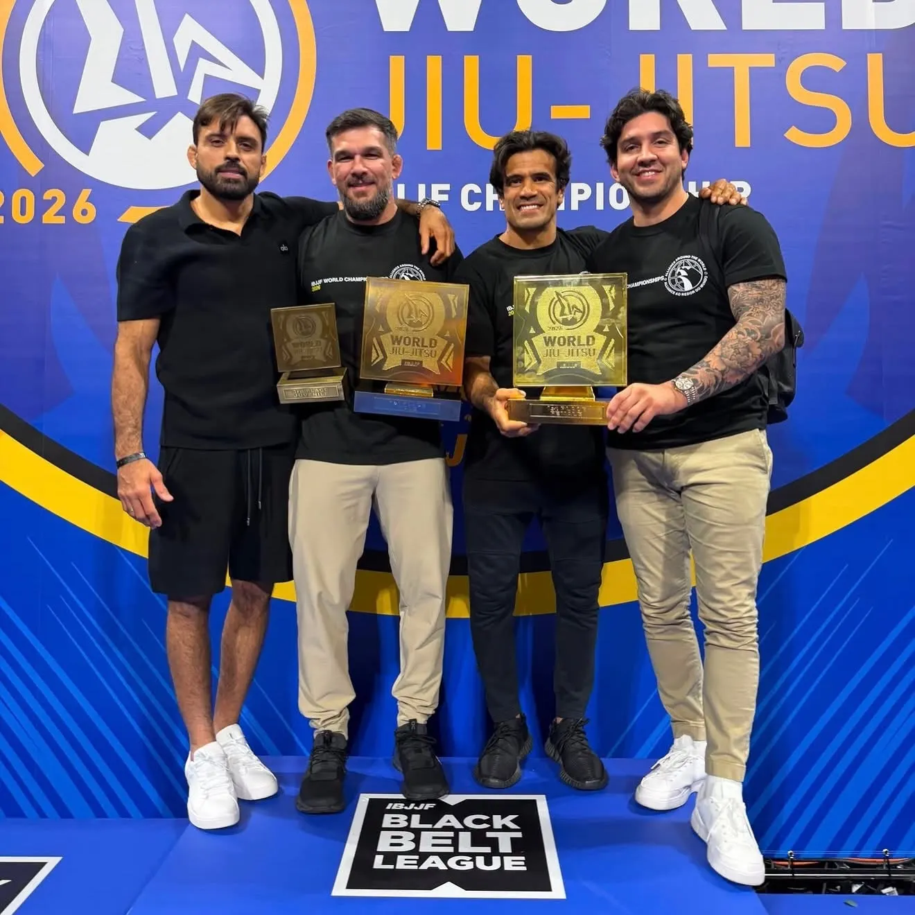 Four men holding trophies on stage at a World Jiu-Jitsu Championship event