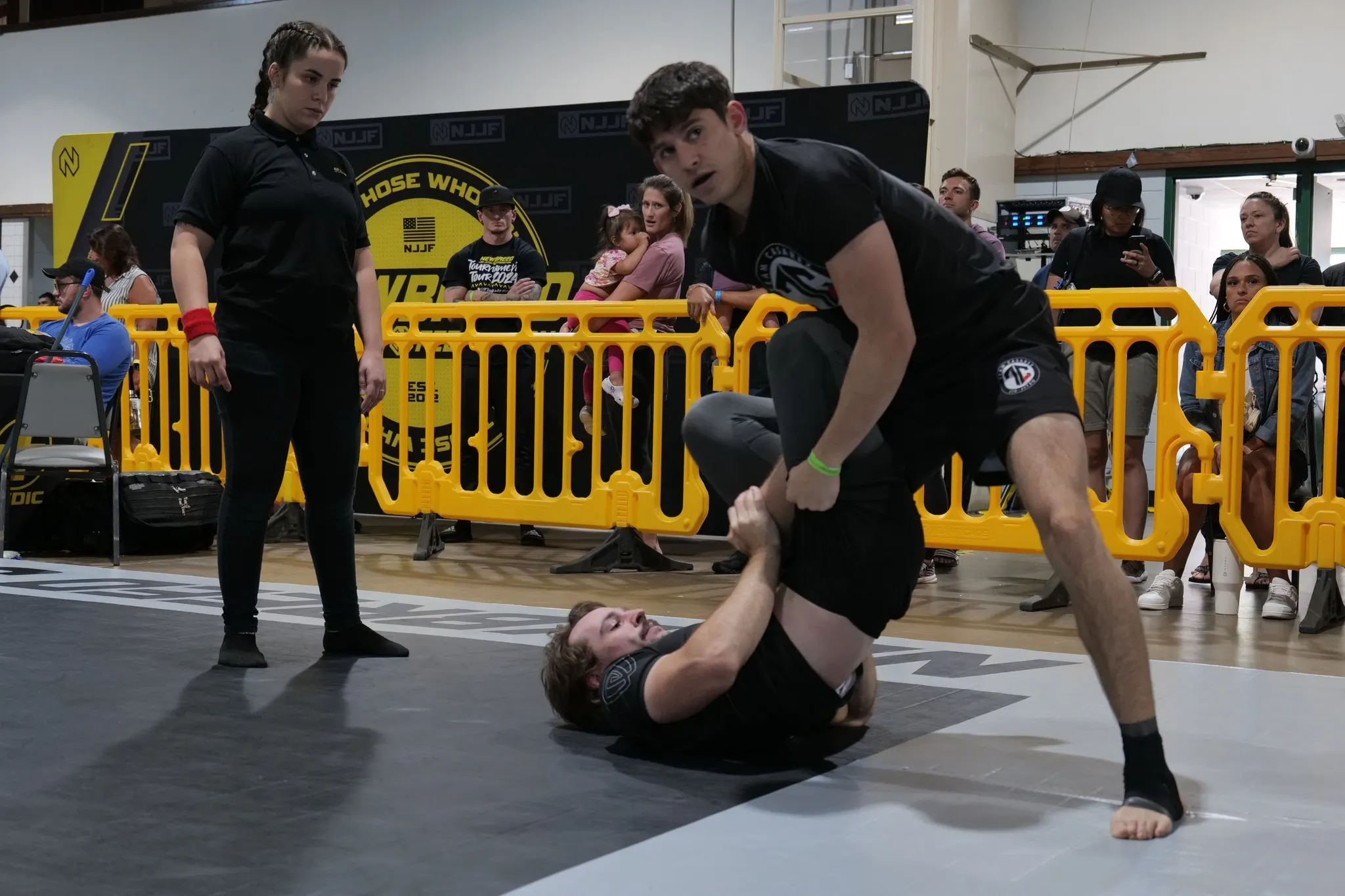 Two grapplers in rash guards and shorts working a guard pass during a No-Gi jiu-jitsu match